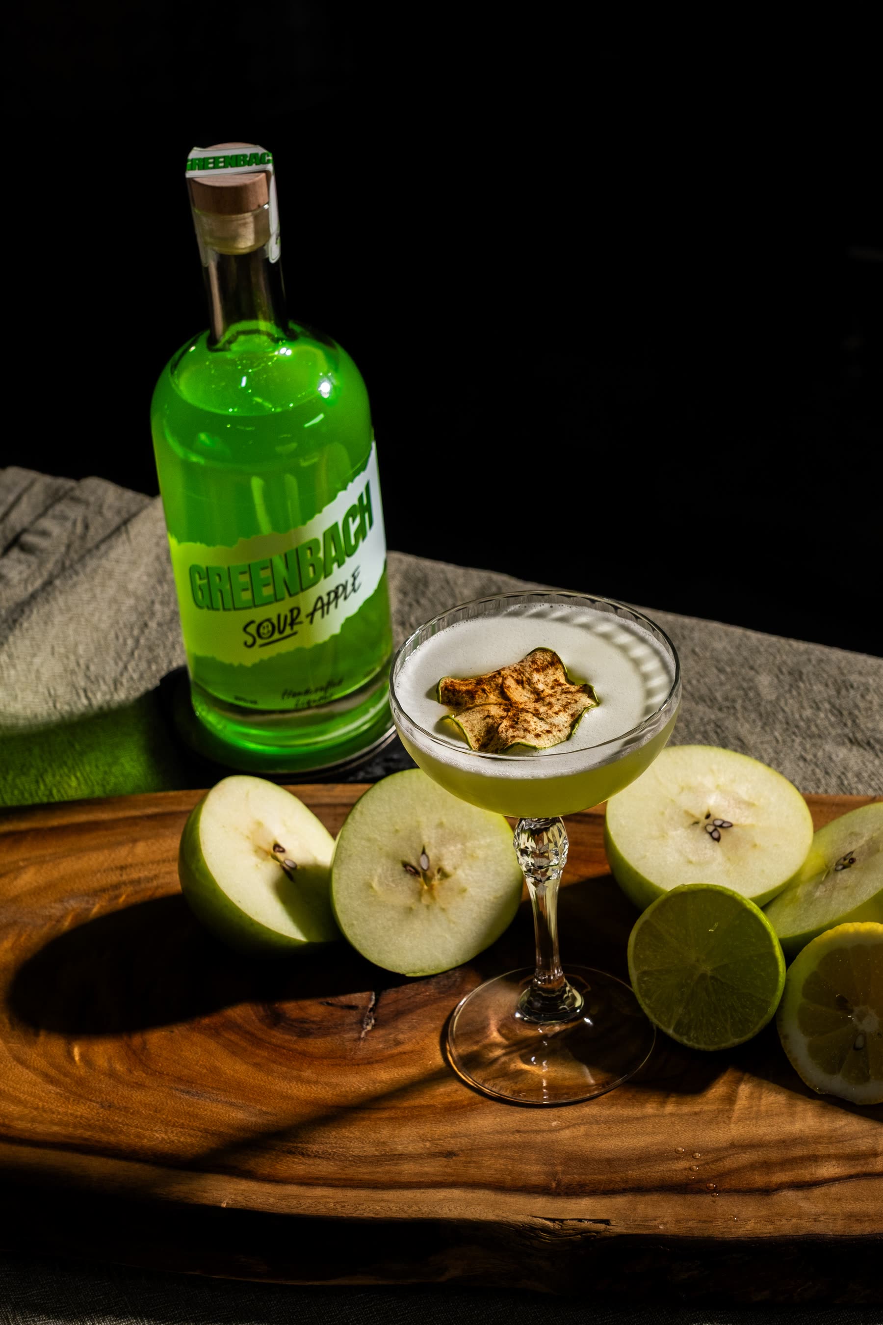 A Greenbach coupe on a timber board with fresh apple, dried apple and lime