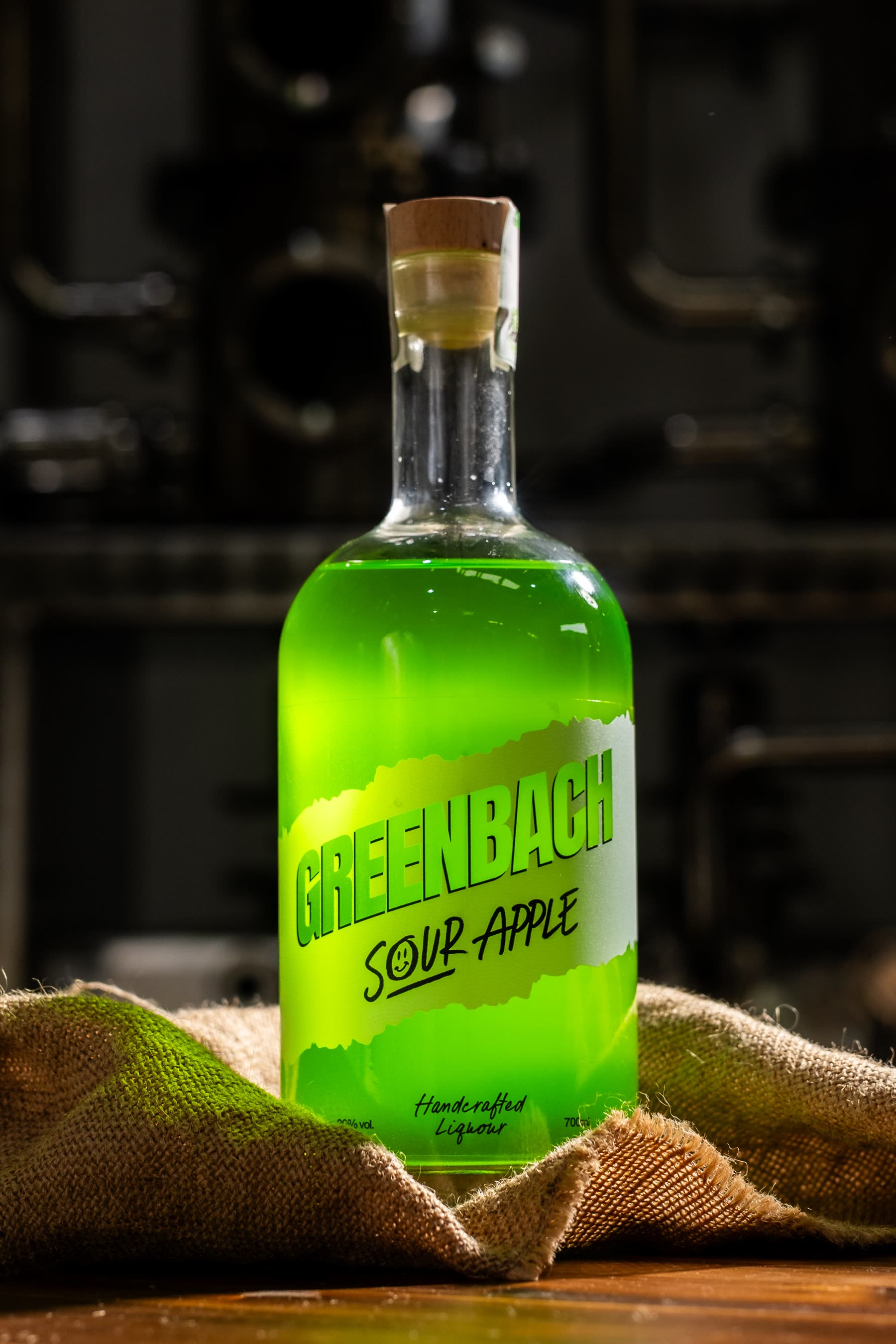 A bottle of Greenbach resting on hessian in front of the still