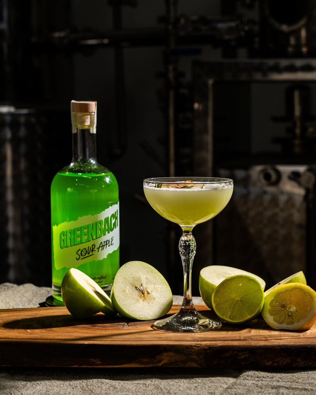A Greenbach sour apple martini beside fresh apple and lime